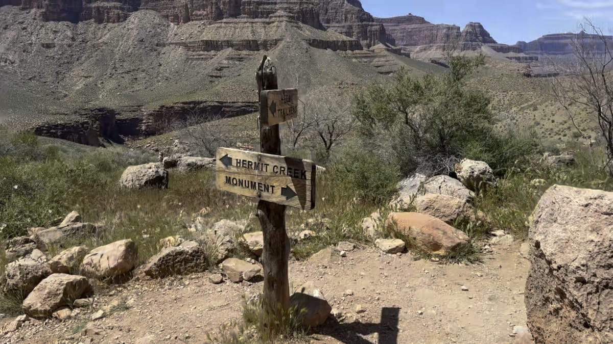 Trail signpost in the Grand Canyon pointing to Hermit Creek Trail and Hermit's Rest Monument.