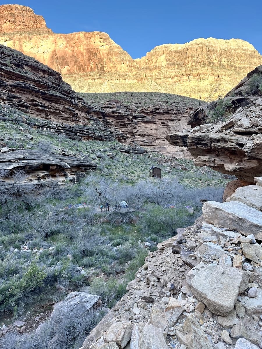 Monument Campsite in Grand Canyon with privy, tents, and canyon views at sunrise.