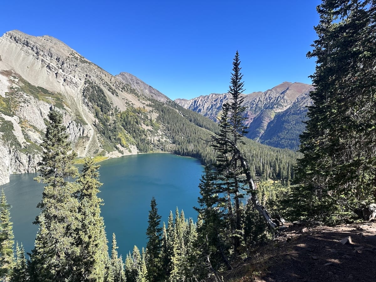 Snowmass Lake view with mountains and evergreen forest.