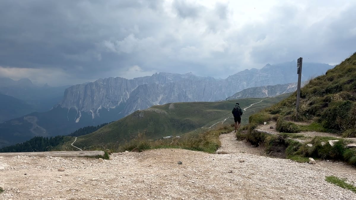Hiker on a rocky path at Forcella di Putia on the Alta Via 2 with Dolomites mountain views.