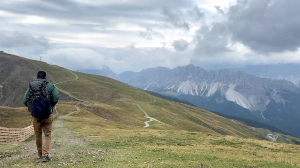 Hiker descending from Rifugio Plose towards the Odle di Eores on the Alta Via 2.
