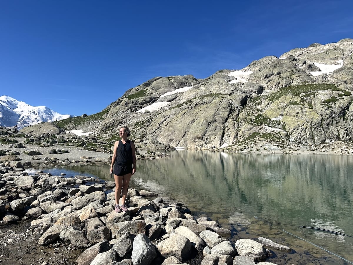 Hiker standing next to Lac Blanc with face towards the warm sun.